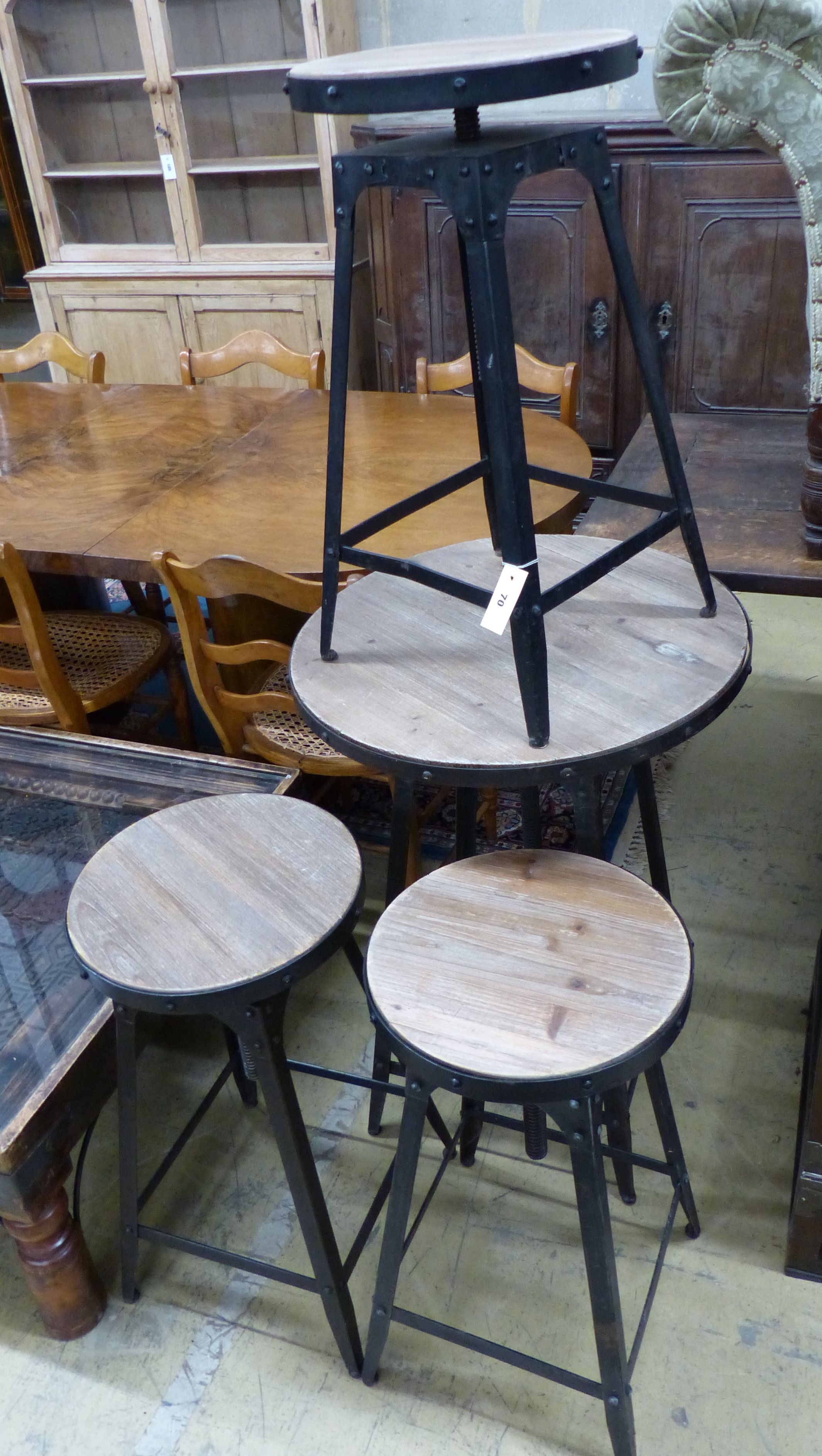 An adjustable wrought iron pub table and three matching telescopic stools